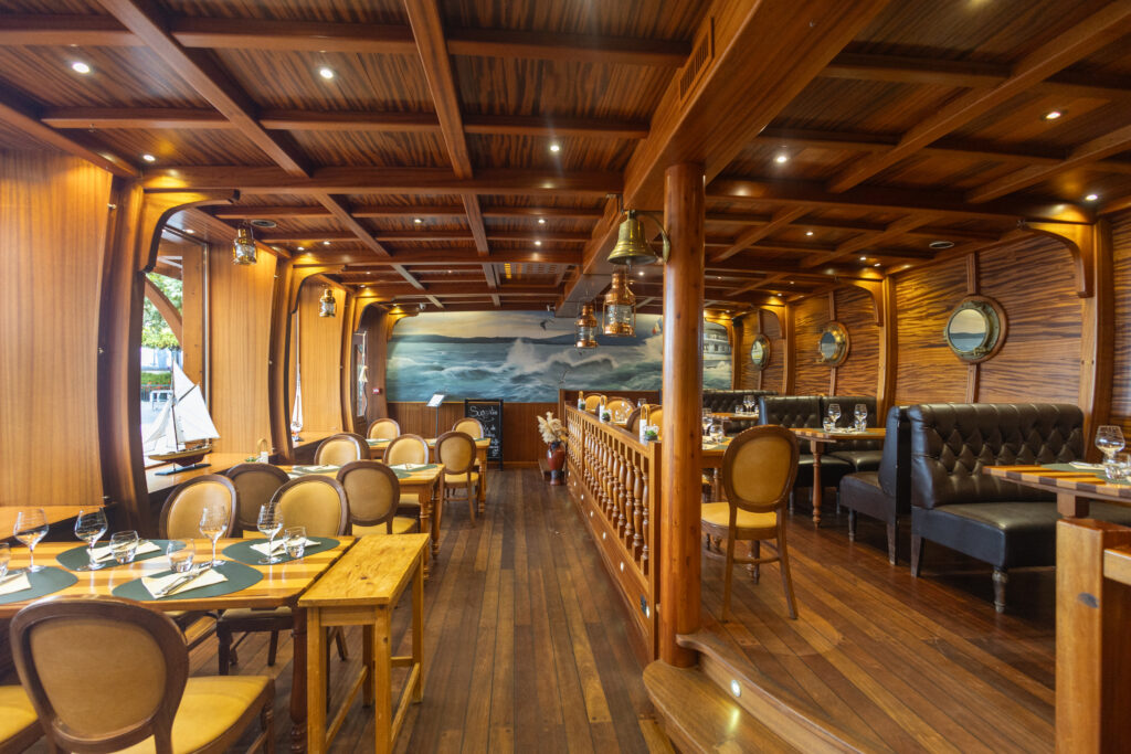 Un écrin chaleureux aux allures de bateau, où boiseries élégantes et lumière tamisée invitent au voyage culinaire sur les rives du Léman