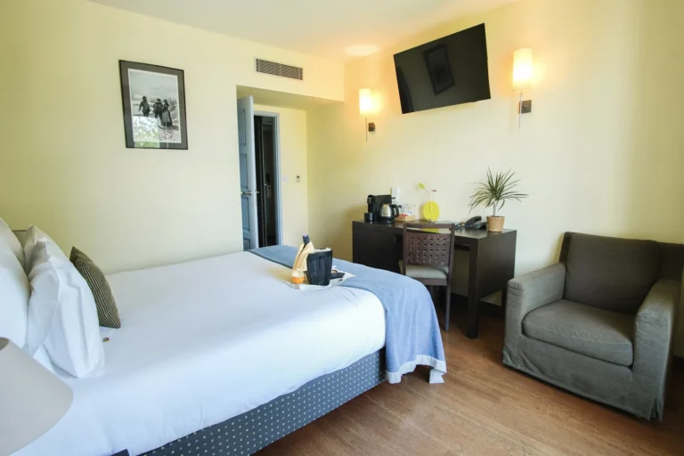 Chambre double avec balcon, lit double et fauteuil gris