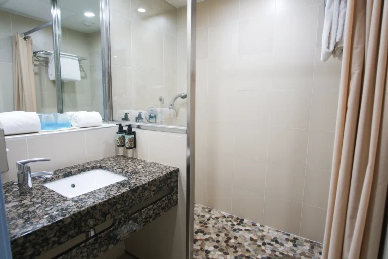 Salle de bain moderne avec douche et vasque en granit, chambre côté lac