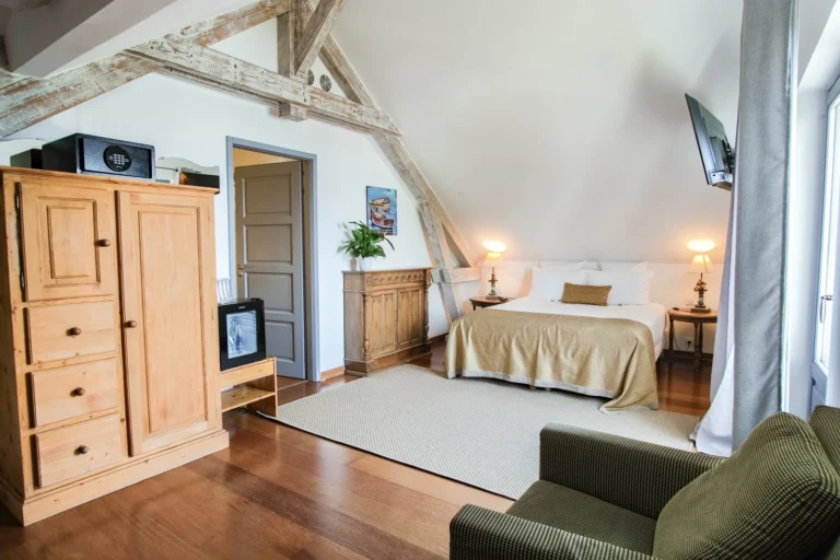 Chambre familiale sous charpente avec lit double et armoire en bois