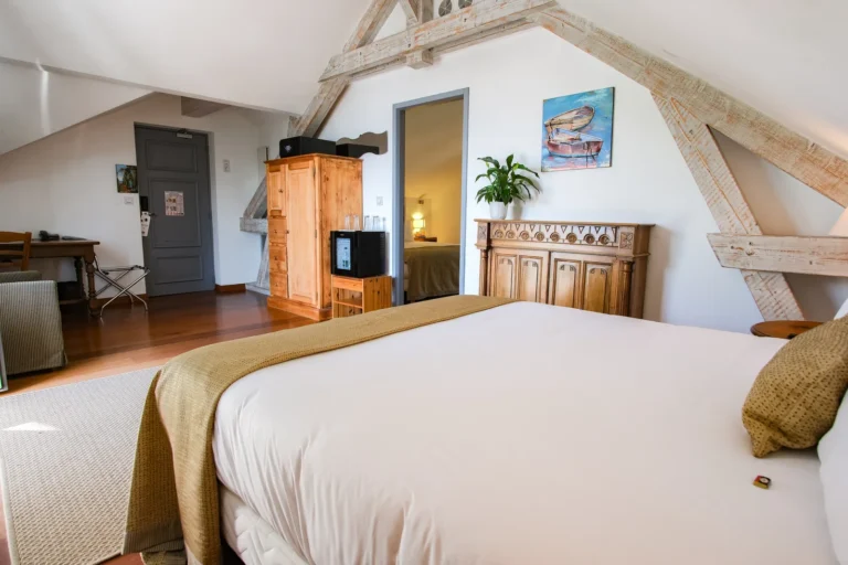 Chambre familiale avec armoire, miroir et poutres blanchies