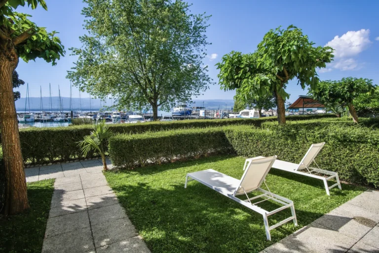 Jardin privatif ombragé avec chaises longues et vue sur le port d'Yvoire