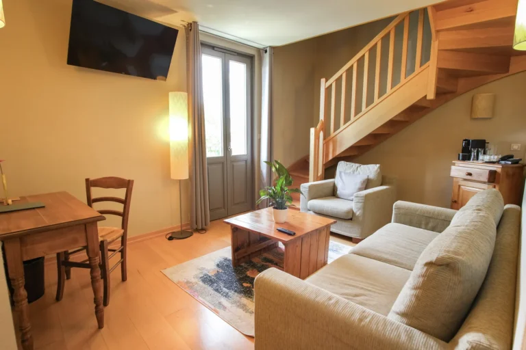 Salon de la suite duplex avec canapé, bureau et escalier en bois