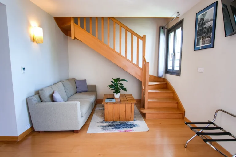 Salon lumineux de la suite duplex avec canapé et escalier
