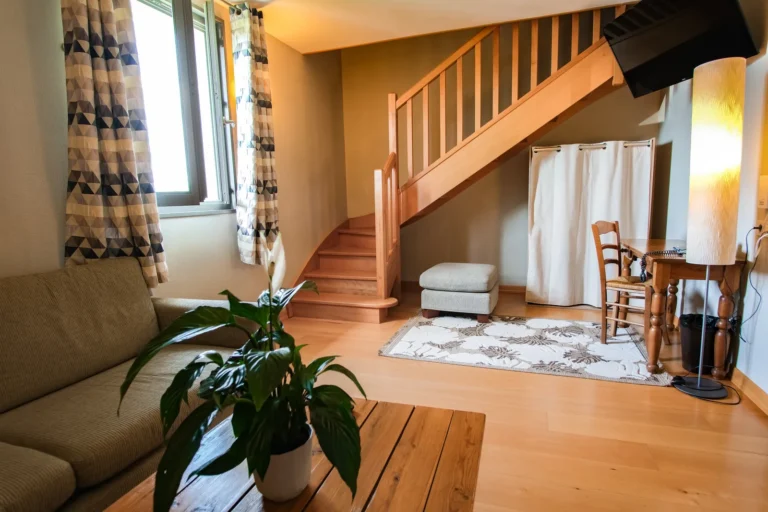 Salon de la suite duplex avec canapé et escalier en bois clair